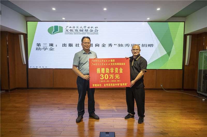 廣西師范大學(xué)出版社集團黨委書(shū)記、董事長(cháng)黃軒莊（左一）代表出版社向金秀民族中學(xué)“獨秀班”資助30萬(wàn)元（李顯楊攝）.jpg