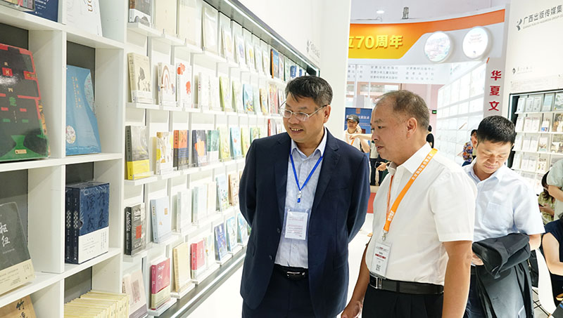 集團公司黨委書(shū)記、董事長(cháng)張藝兵向校黨委副書(shū)記趙鐵詳細介紹出版社圖書(shū)（陳子鋒攝）.JPG